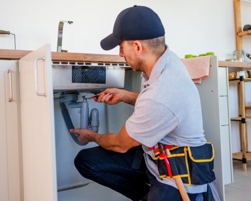 Plumber installing plumbing connections for a household appliance.